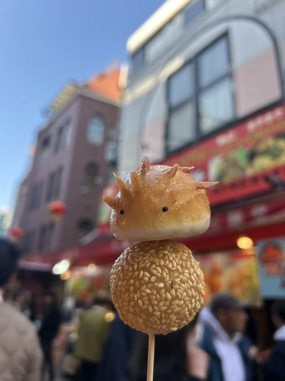 南京町の名物ハリネズミ饅頭とごま団子の2段串（青空背景でSNS映え）