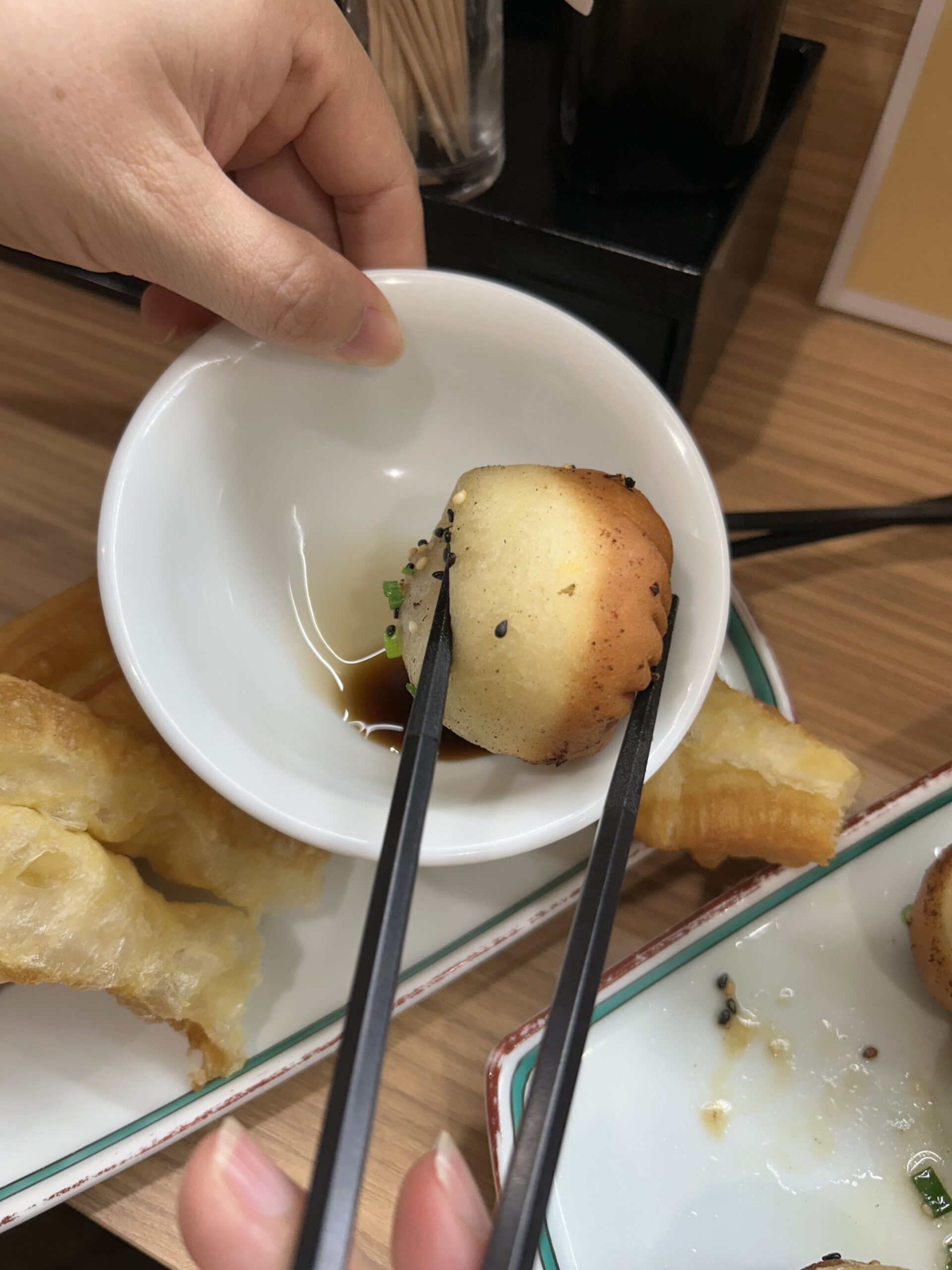 上海焼き小籠包を酢醤油につけて食べる様子。皮の中から肉汁があふれる