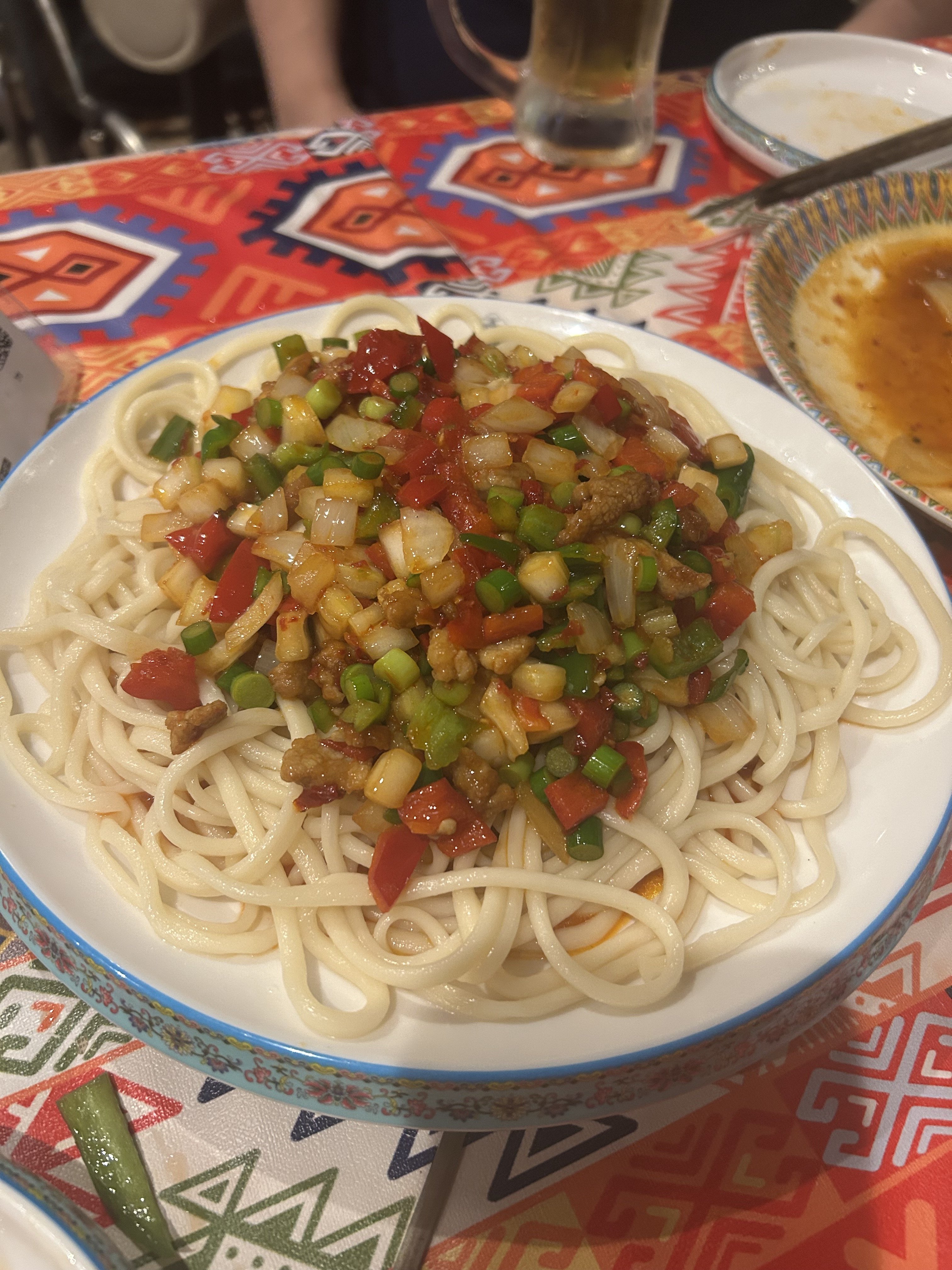 アリババのラグメン。手打ちの白い太麺の上にトマト・パプリカ・ピーマン・羊肉細切りの炒めソースがたっぷり乗ったウイグルの代表麺料理