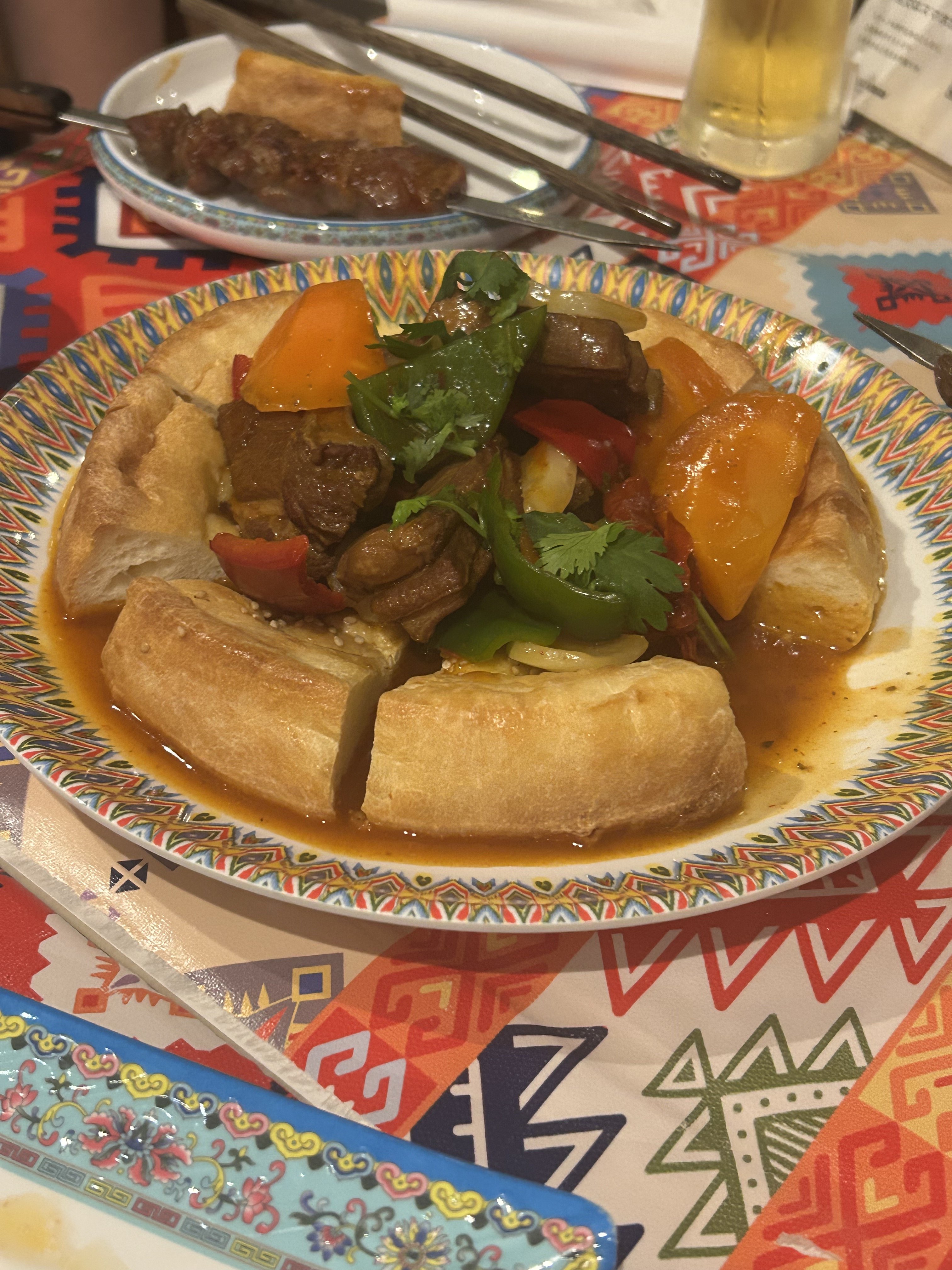 アリババのナン包み肉。輪っか状のナンの中央に羊肉・パプリカ・トマト・パクチーの煮込みが乗った、ウイグルを代表する看板料理