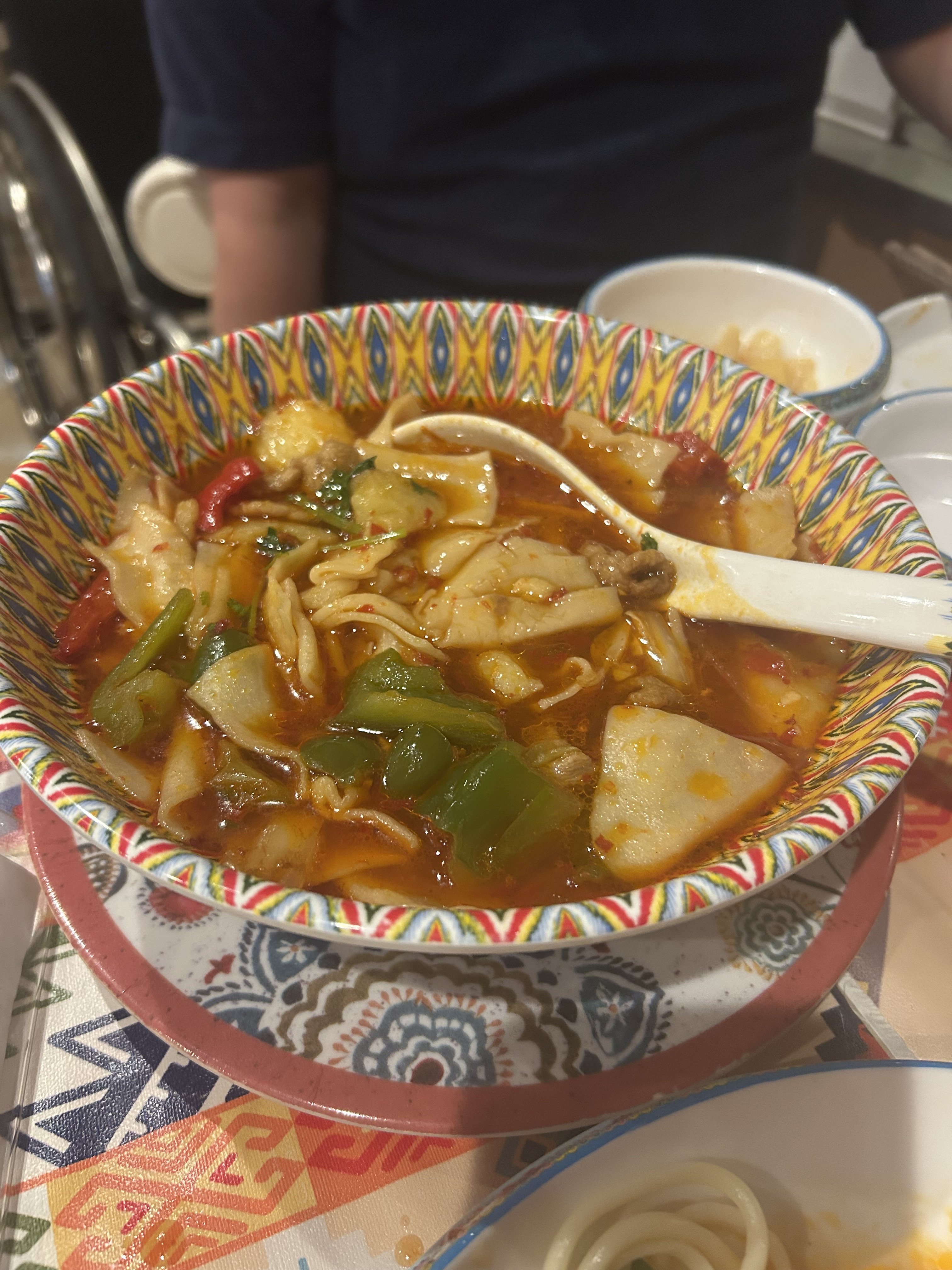 アリババの薄手延ばし麺のスープ。羊肉・ピーマン・パプリカ・きのこ入りの辛味スープに、手で薄く伸ばした短い麺片が浮かぶ